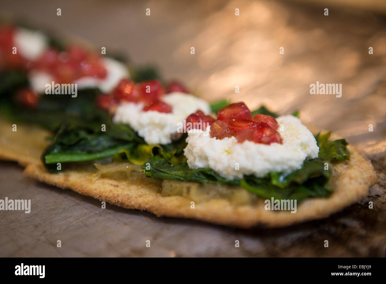 Tapas spagnoli con spinaci, formaggio morbido e i semi di melograno su flatbread Foto Stock