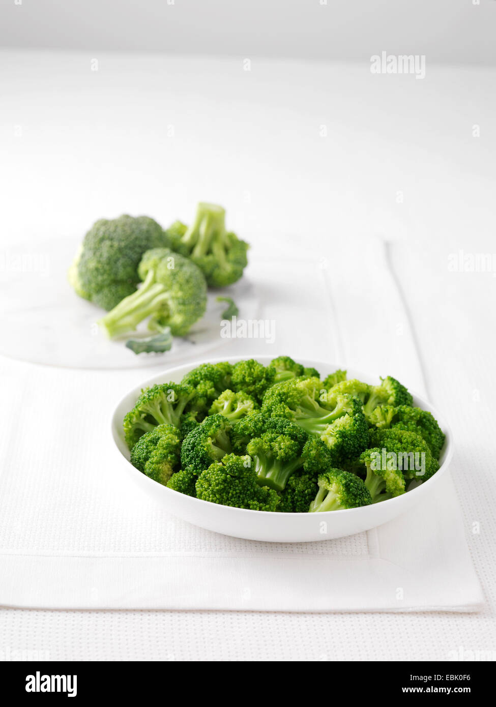 Materie broccoli su marmo tagliere e ciotola di bollito broccoli Foto Stock