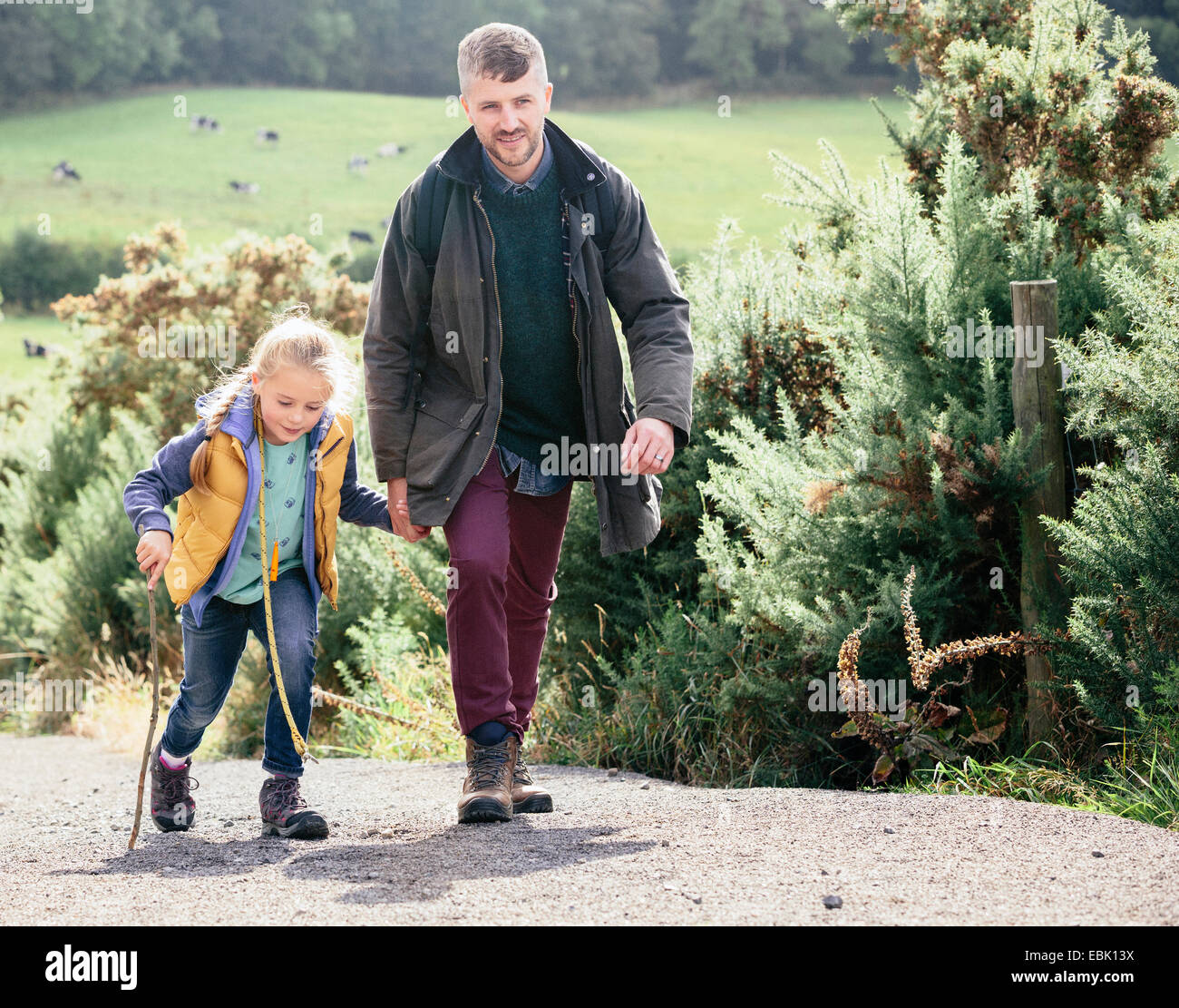 Padre e figlia escursionismo su strada rurale Foto Stock