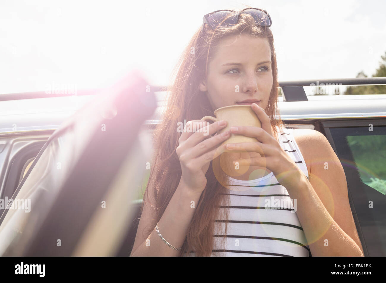 Giovane donna con pausa caffè sul viaggio su strada Foto Stock