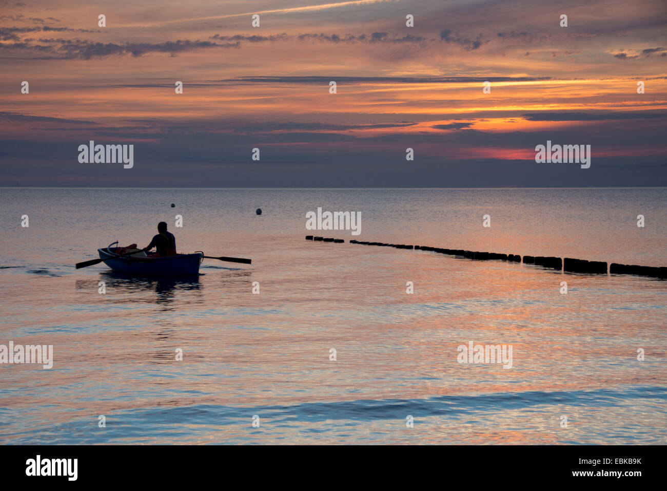 Uomo in barca da pesca barca a remi per la spiaggia nella luce della sera, Germania, Meclemburgo-Pomerania, Hiddensee Foto Stock