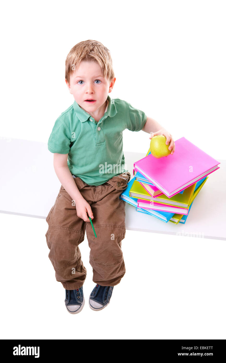 Ragazzino con i libri con una pila di libri e un apple Foto Stock