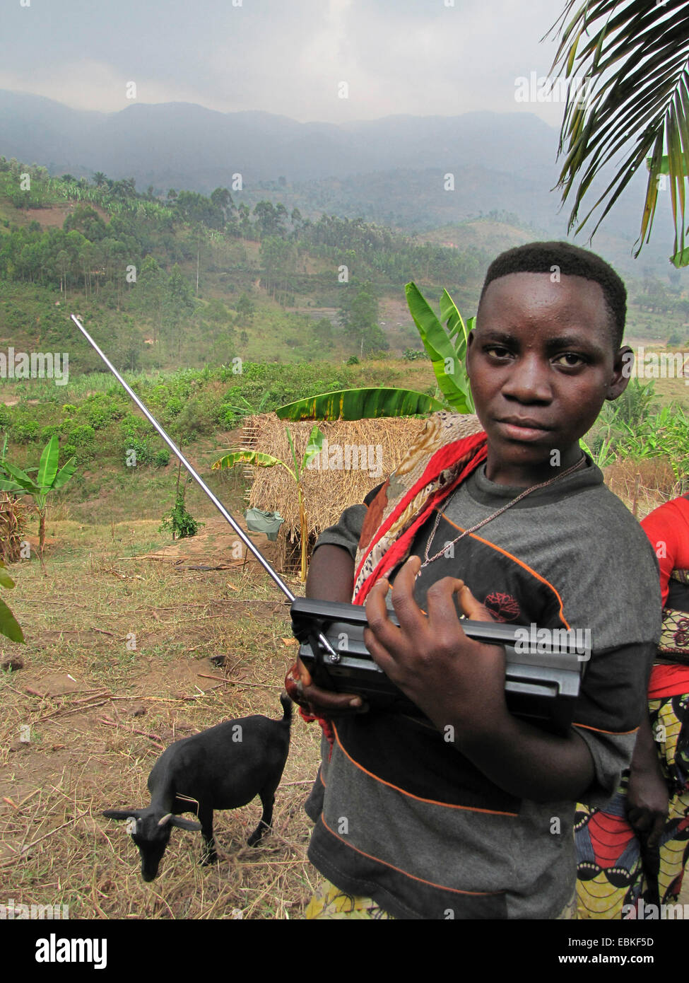 Giovane donna con radio nella parte anteriore del paesaggio collinare, membro della minoranza dei Batwa, Burundi Bujumbura rurale, Mutimbuzi Foto Stock