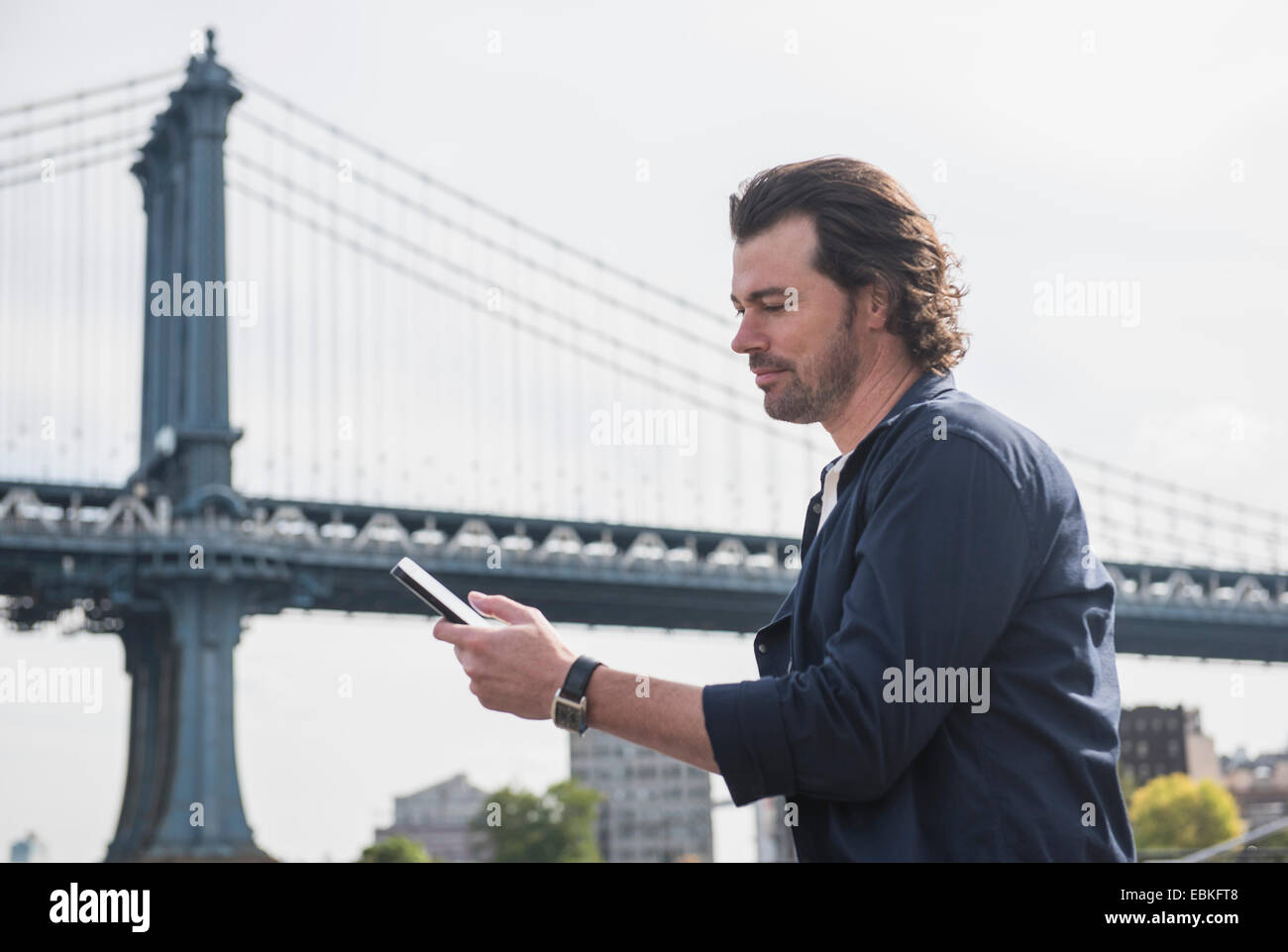 Stati Uniti d'America, nello Stato di New York, New York, Brooklyn, uomo utilizzando tablet pc, Manhattan Bridge in background Foto Stock
