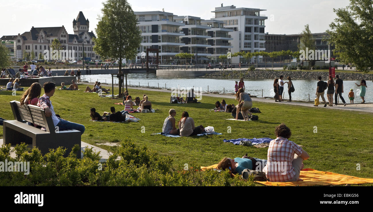 Persone che giace nel prato vicino al lago di Phoenix in primavera, Medical Center e Hoerde castel in sfondo , in Germania, in Renania settentrionale-Vestfalia, la zona della Ruhr, Dortmund Foto Stock
