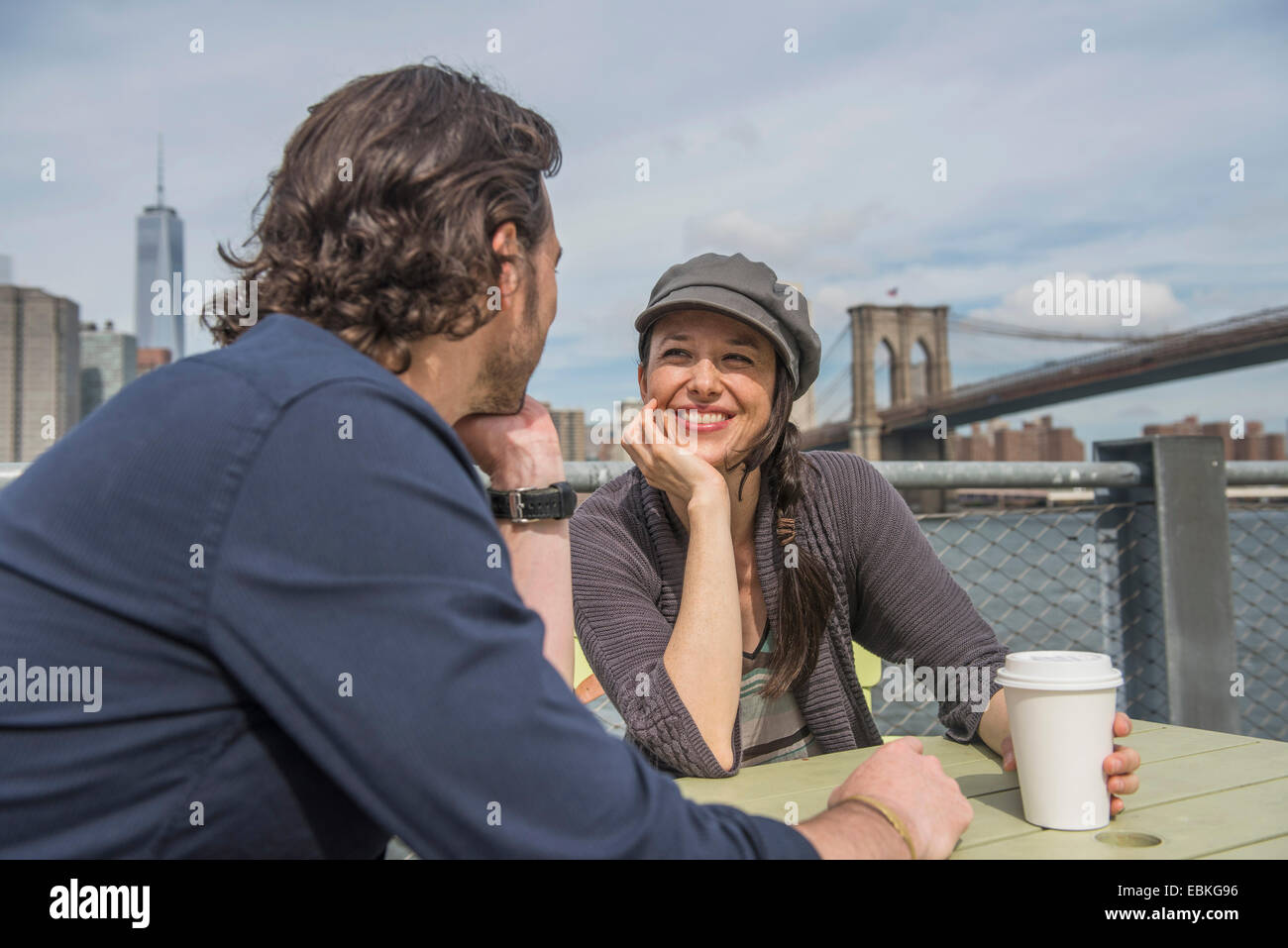 Stati Uniti d'America, nello Stato di New York, New York, Brooklyn, felice coppia seduta e di discutere con il paesaggio urbano in background Foto Stock
