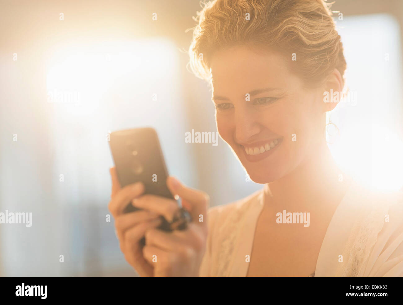 Sorridente giovane donna utilizzando il telefono cellulare Foto Stock
