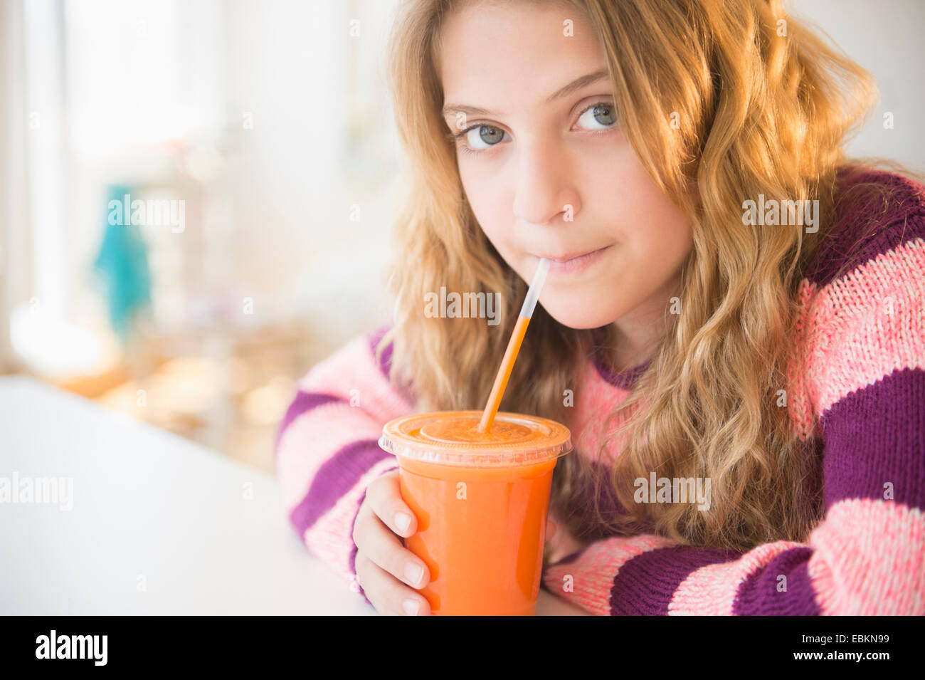 La ragazza (12-13) sorseggiando un succo di carota Foto Stock