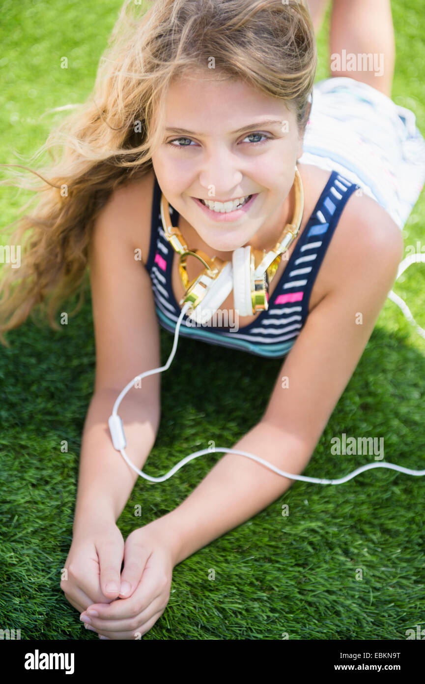 La ragazza (12-13) giacenti in erba con le cuffie Foto Stock