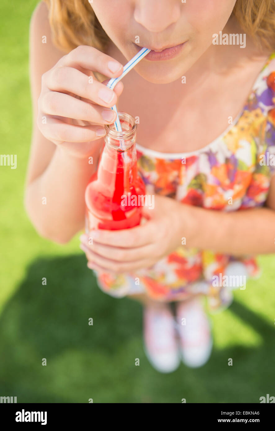 La ragazza (12-13) di soda bere dalla bottiglia usando la paglia Foto Stock