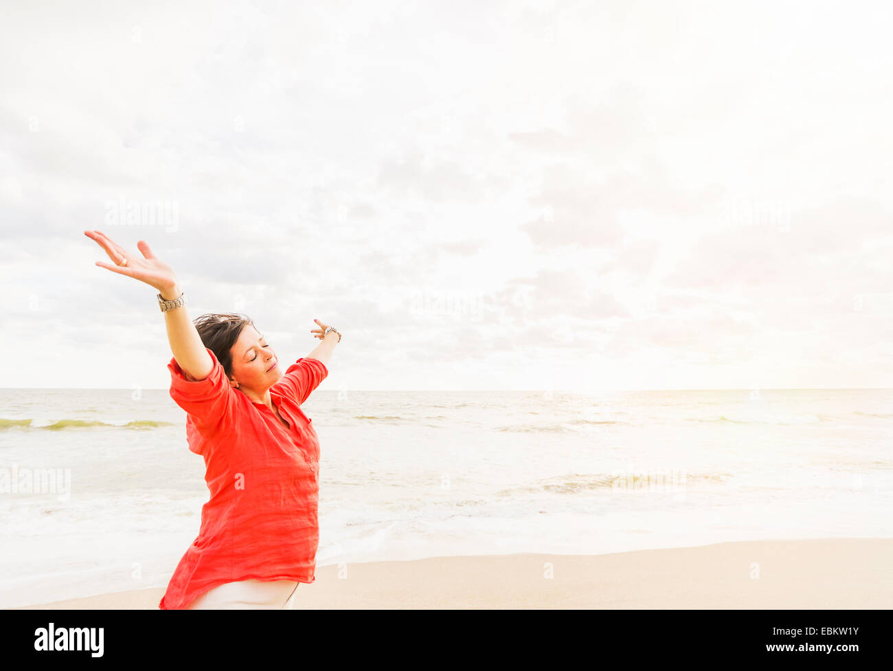 Stati Uniti d'America, Florida, Giove, vista laterale della donna in piedi con le braccia in alto sulla spiaggia Foto Stock