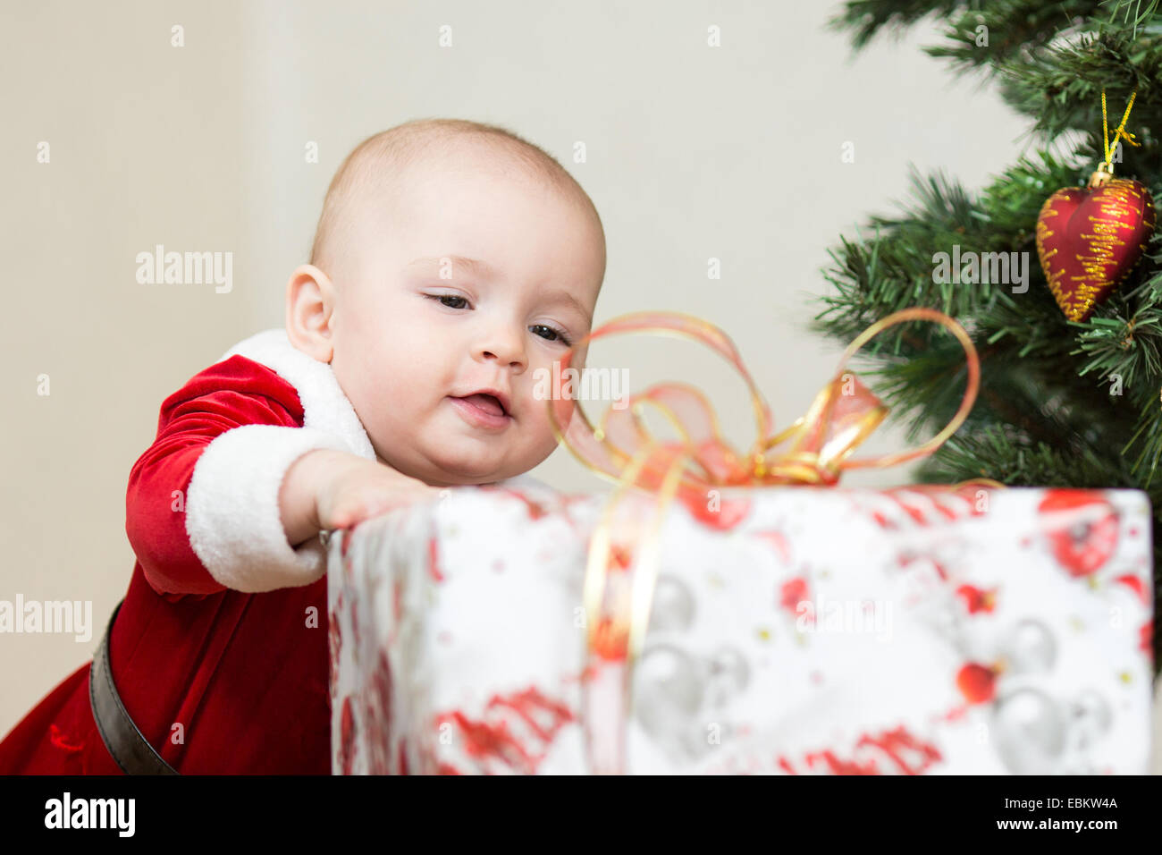 Bambino con grande confezione regalo su albero di Natale sfondo Foto Stock