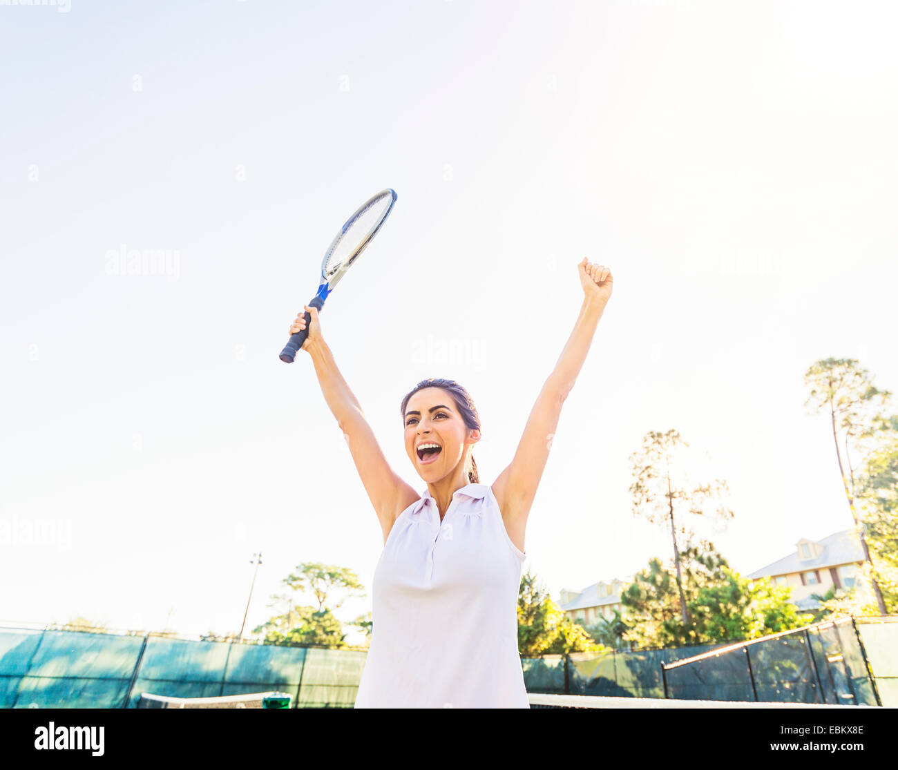 Stati Uniti d'America, Florida, Giove, Ritratto di giovane donna holding racchetta da tennis, i bracci di sollevamento in festa Foto Stock