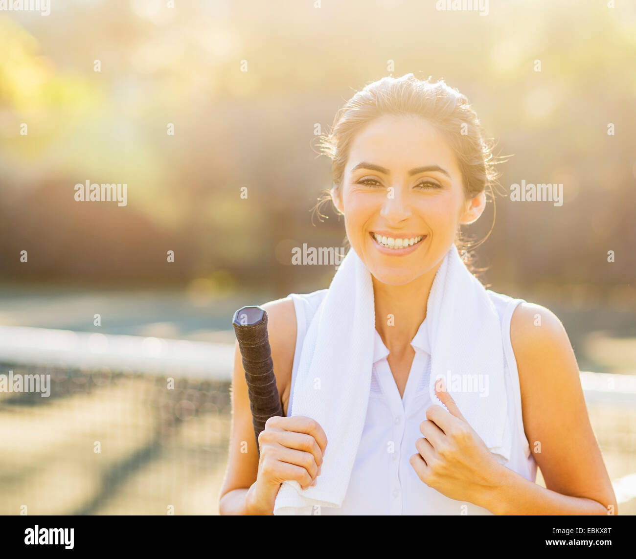 Ritratto di sorridente giovane donna con asciugamano e racchetta da tennis Foto Stock
