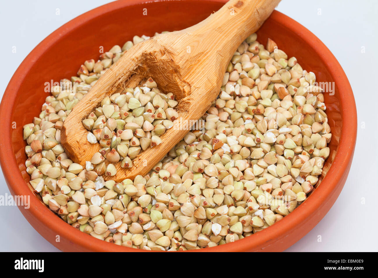 Il grano saraceno (Fagopyrum esculentum), semi nel piatto con un cucchiaio di legno Foto Stock