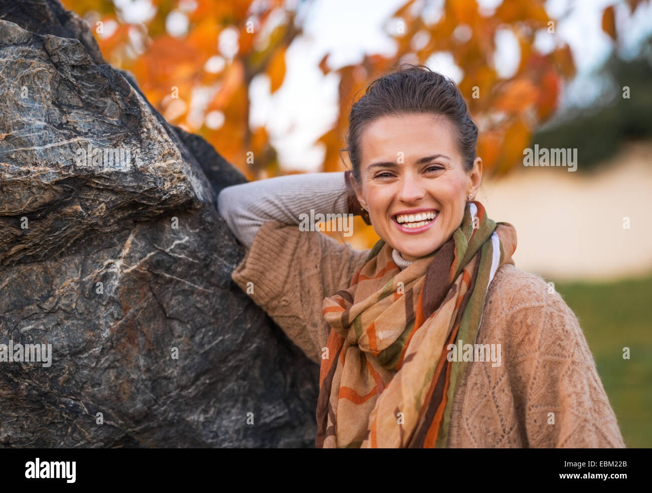 Ritratto di sorridente giovane donna in autunno all'aperto in serata Foto Stock