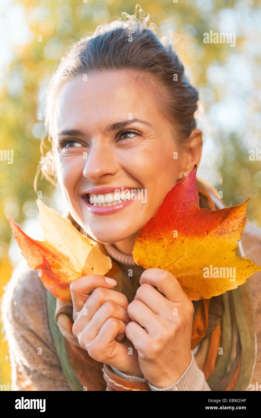 Ritratto di felice giovane donna con foglie di autunno all'aperto Foto Stock