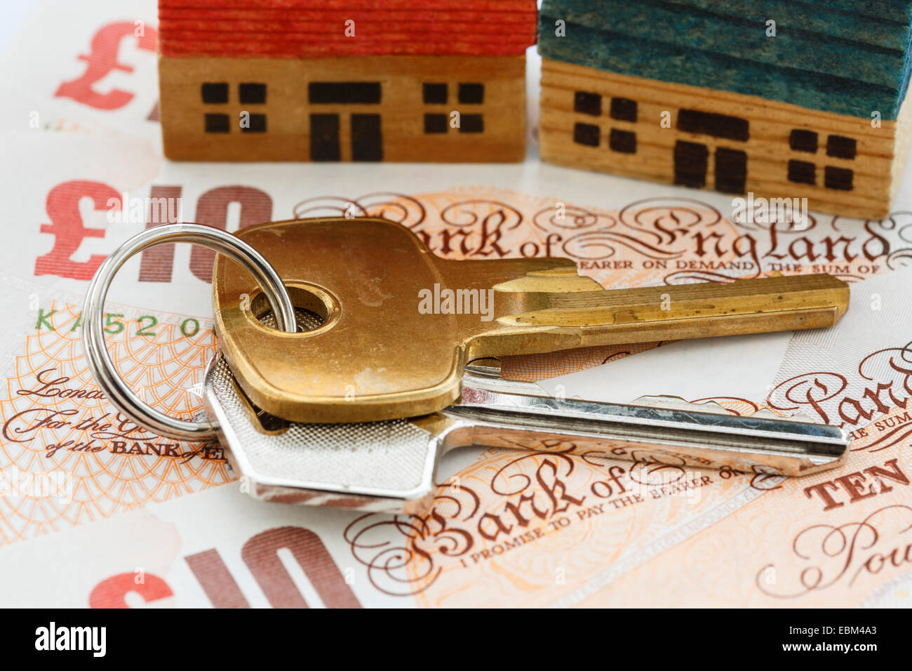 Casa porta chiavi sul denaro sterling dieci note sterlina GBP con due case per illustrare la scaletta di proprietà e i valori del portafoglio concetto in Inghilterra UK Gran Bretagna Foto Stock