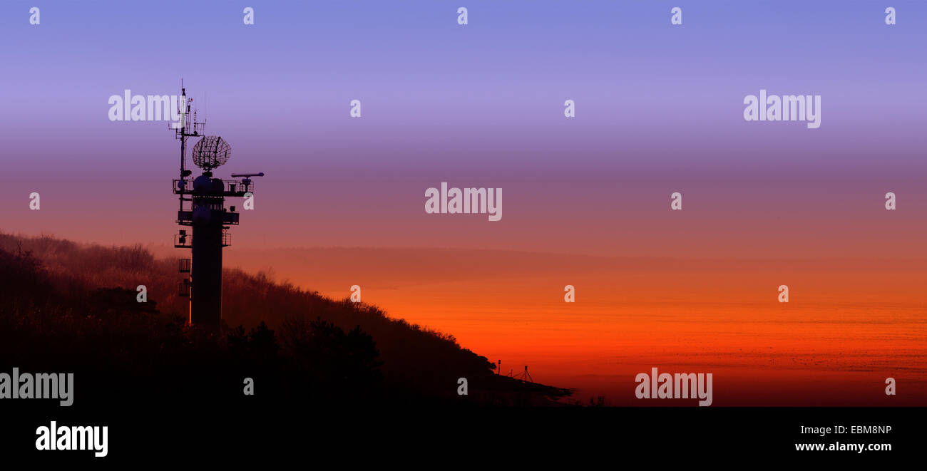 Silhouette di una stazione radar sulla costa polacca al tramonto. Foto Stock