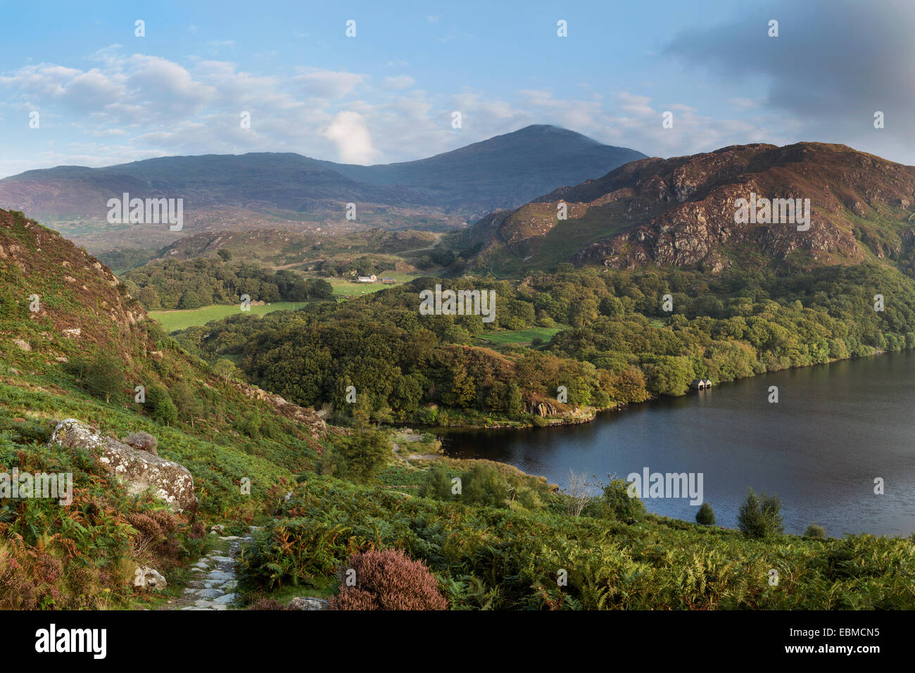 La mattina di sole illumina le colline e le montagne che circondano Llyn Dinas, Snowdonia, il Galles del Nord Foto Stock
