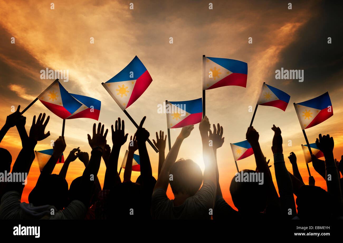 Gruppo di persone sventolando bandiere filippini nel retro illuminato Foto Stock