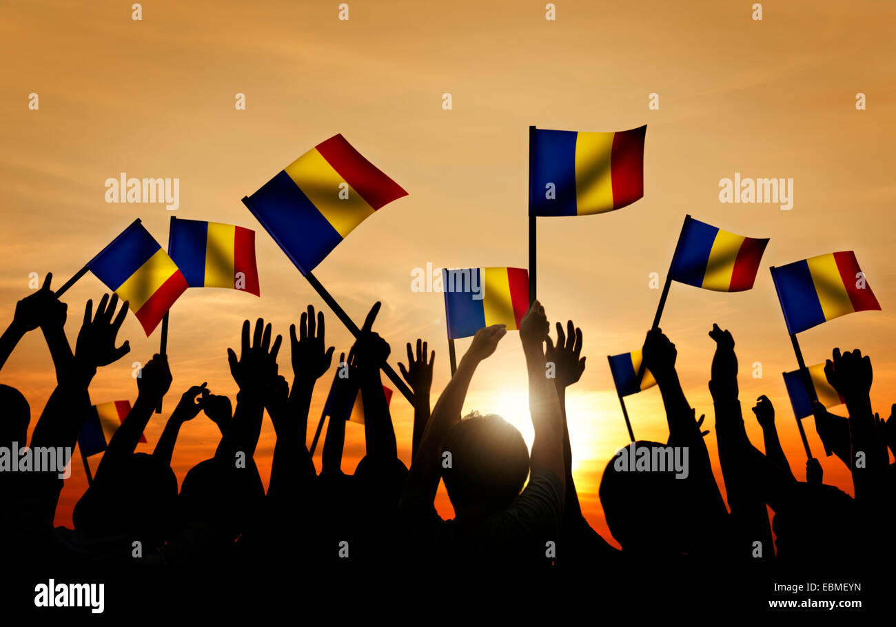 Gruppo di persone sventolando bandiere rumene nel retro illuminato Foto Stock