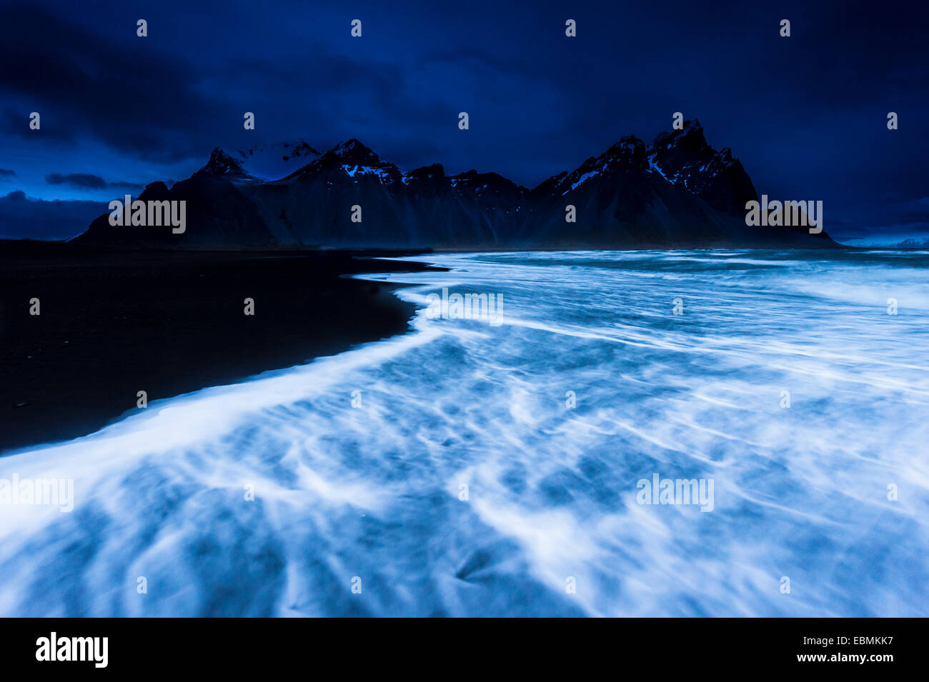 Picchi di montagna e surf, blu ora, Höfn, Islanda Foto Stock