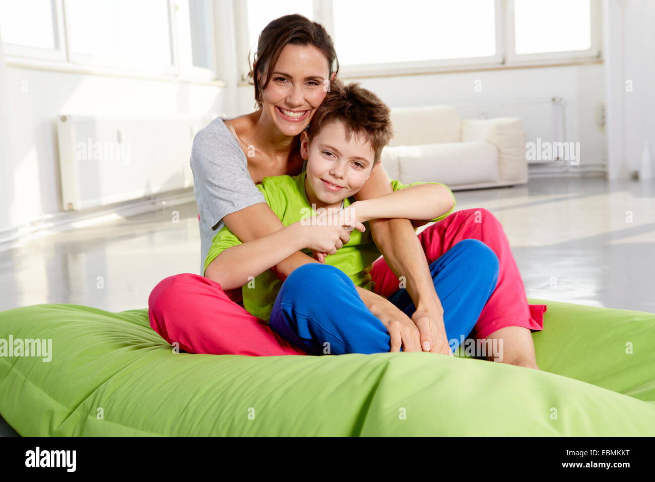 Madre e figlio in abiti casual seduto su una beanbag in un loft, Germania Foto Stock