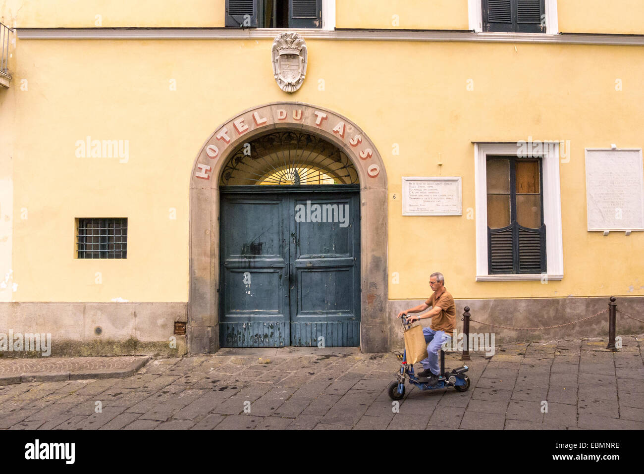 Un uomo su uno scooter passa il Hotel du Tasso di Sorrento, Italia. Foto Stock