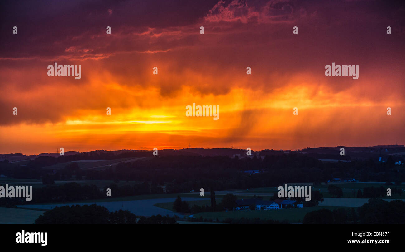 Tempesta di pioggia pesante nella parte anteriore del rosso del cielo della sera, in Germania, in Baviera, Isental, Dorfen Foto Stock