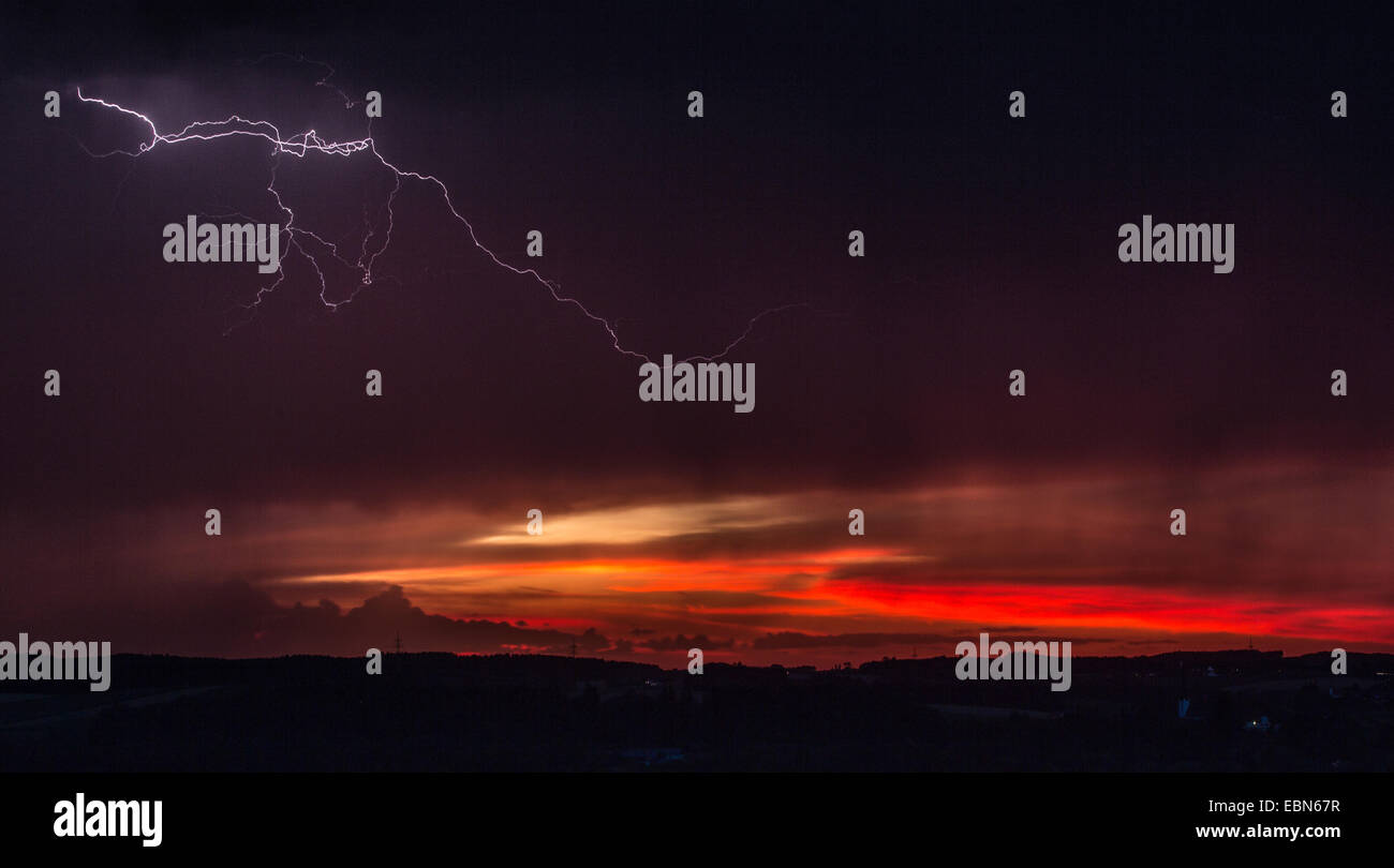 Thundercloud con fulmini nella parte anteriore del rosso del cielo della sera, in Germania, in Baviera, Isental Foto Stock