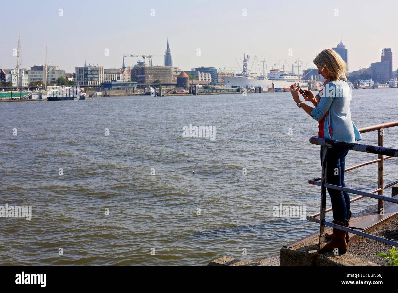 Una donna scatta una fotografia della riva nord dell'Elba sul suo cellulare ad Amburgo in Germania Foto Stock