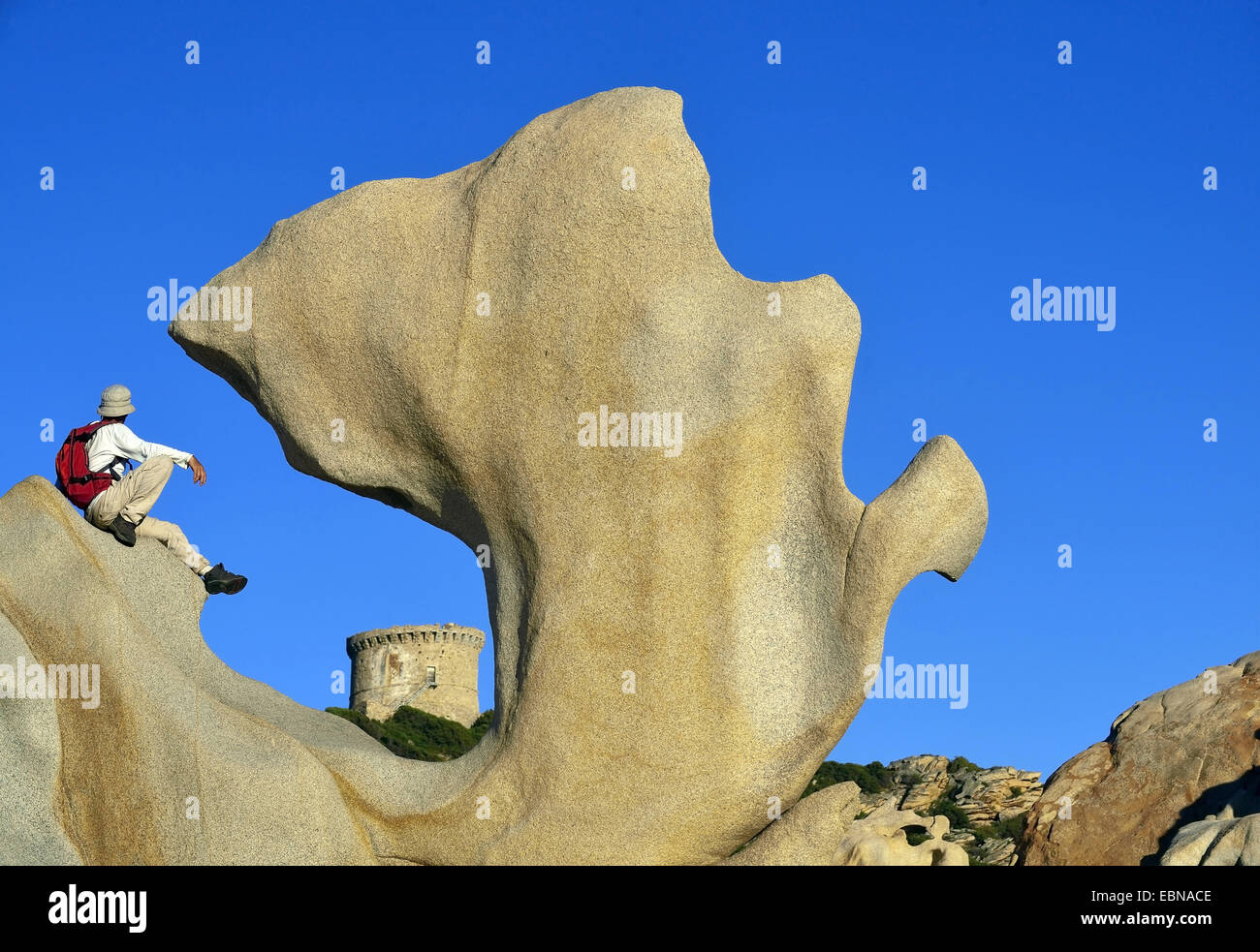 Wanderer seduto su una forma stranamente rock e guardando alla torre di Campomoro , Francia, Corsica Foto Stock
