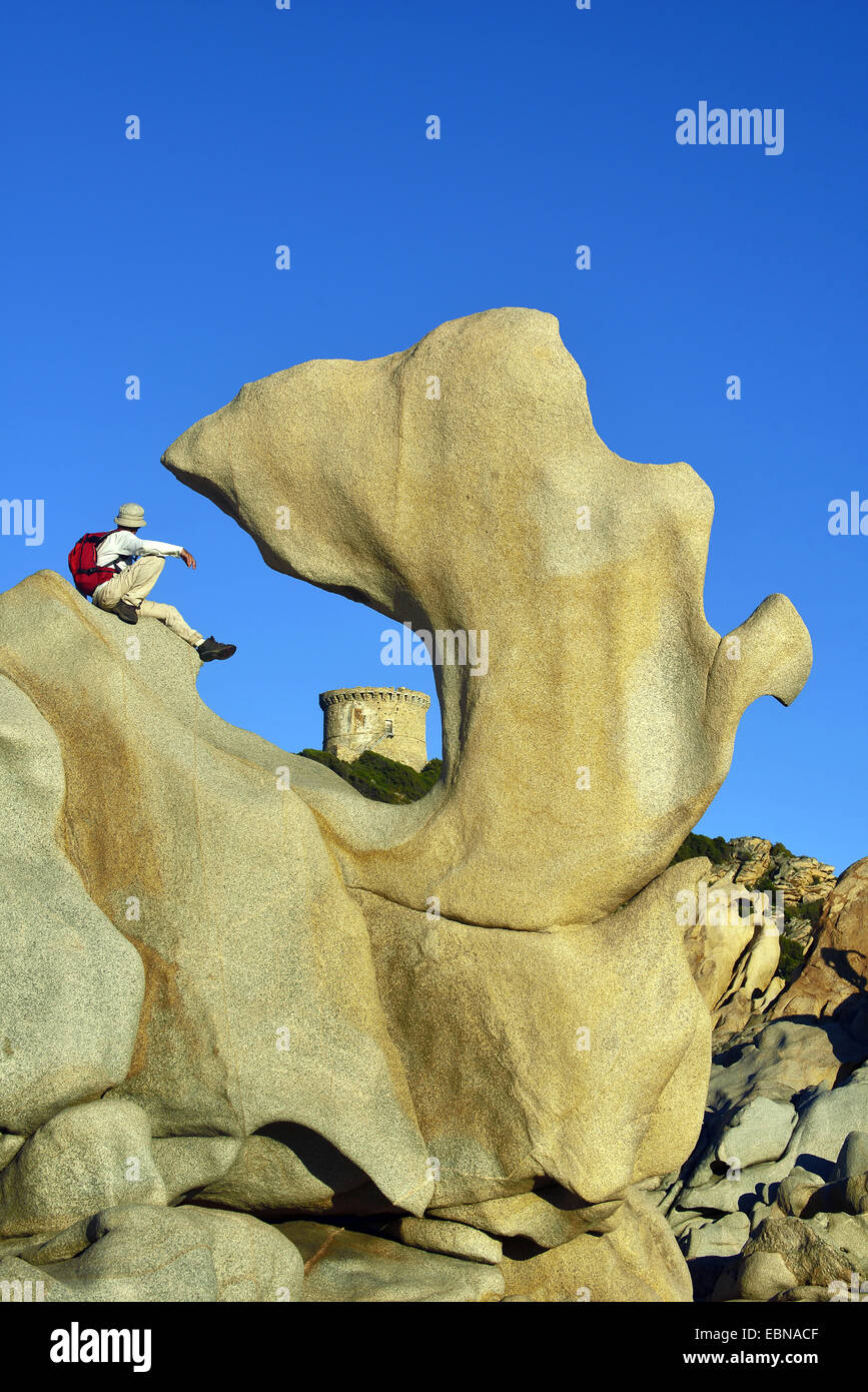 Wanderer seduto su una forma stranamente rock e guardando alla torre di Campomoro , Francia, Corsica Foto Stock