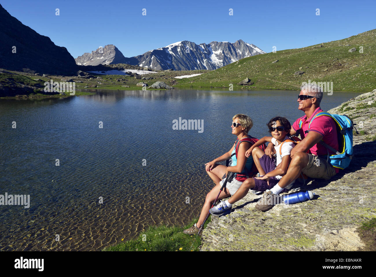 Famiglia seduto su una roccia al lago di Moutons, Francia, Savoie, Parco Nazionale della Vanoise Foto Stock