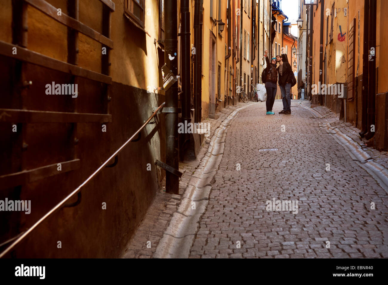 Due turisti prendendo un selfie in una stretta strada di Gamla Stan Città Vecchia , Stoccolma, Svezia Foto Stock