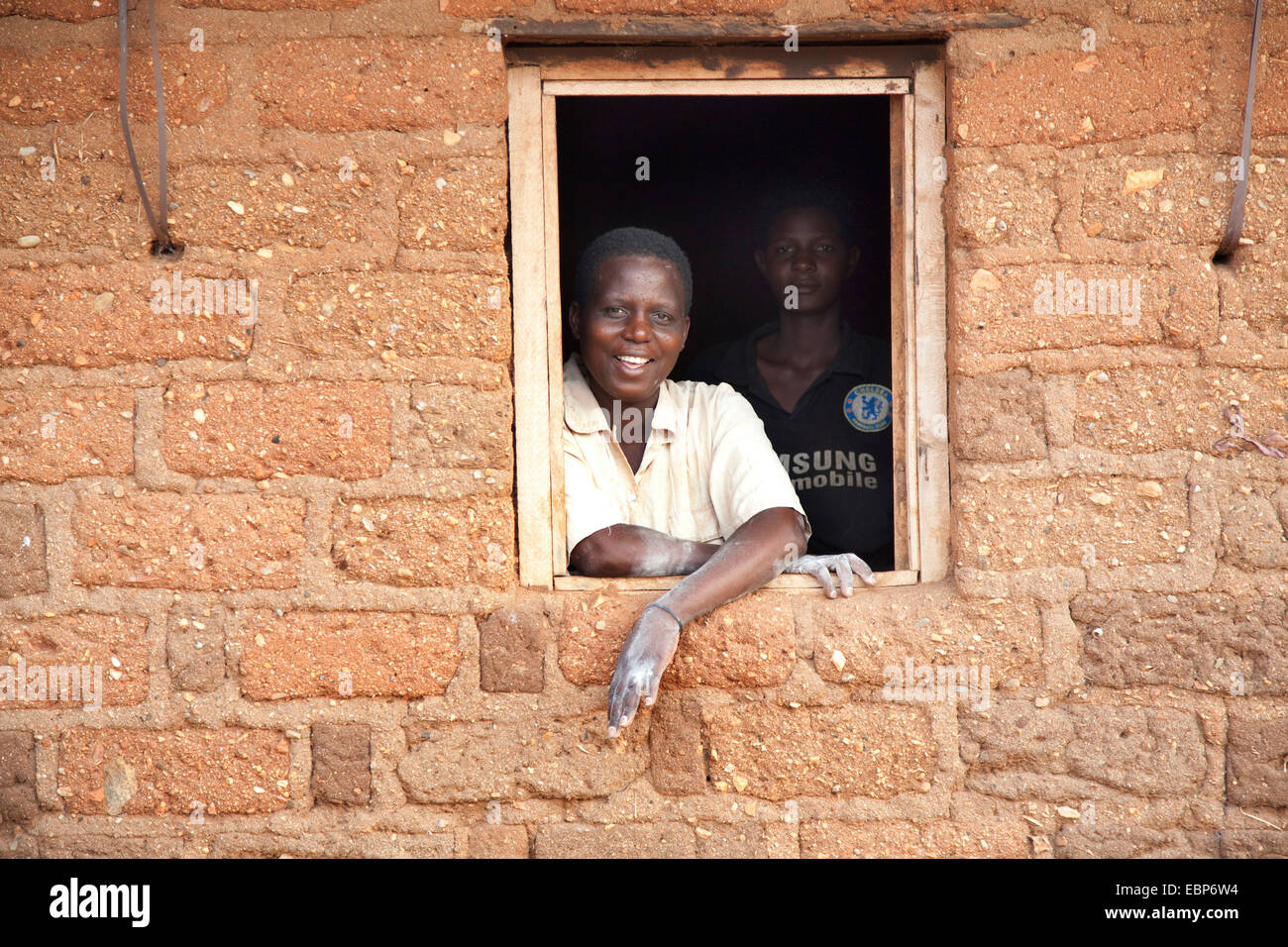 Due donne guardando fuori dalla finestra di una casa di mattoni dove fanno il cibo di farina di granturco, Burundi, Mvugo, Nyanza Lac Foto Stock