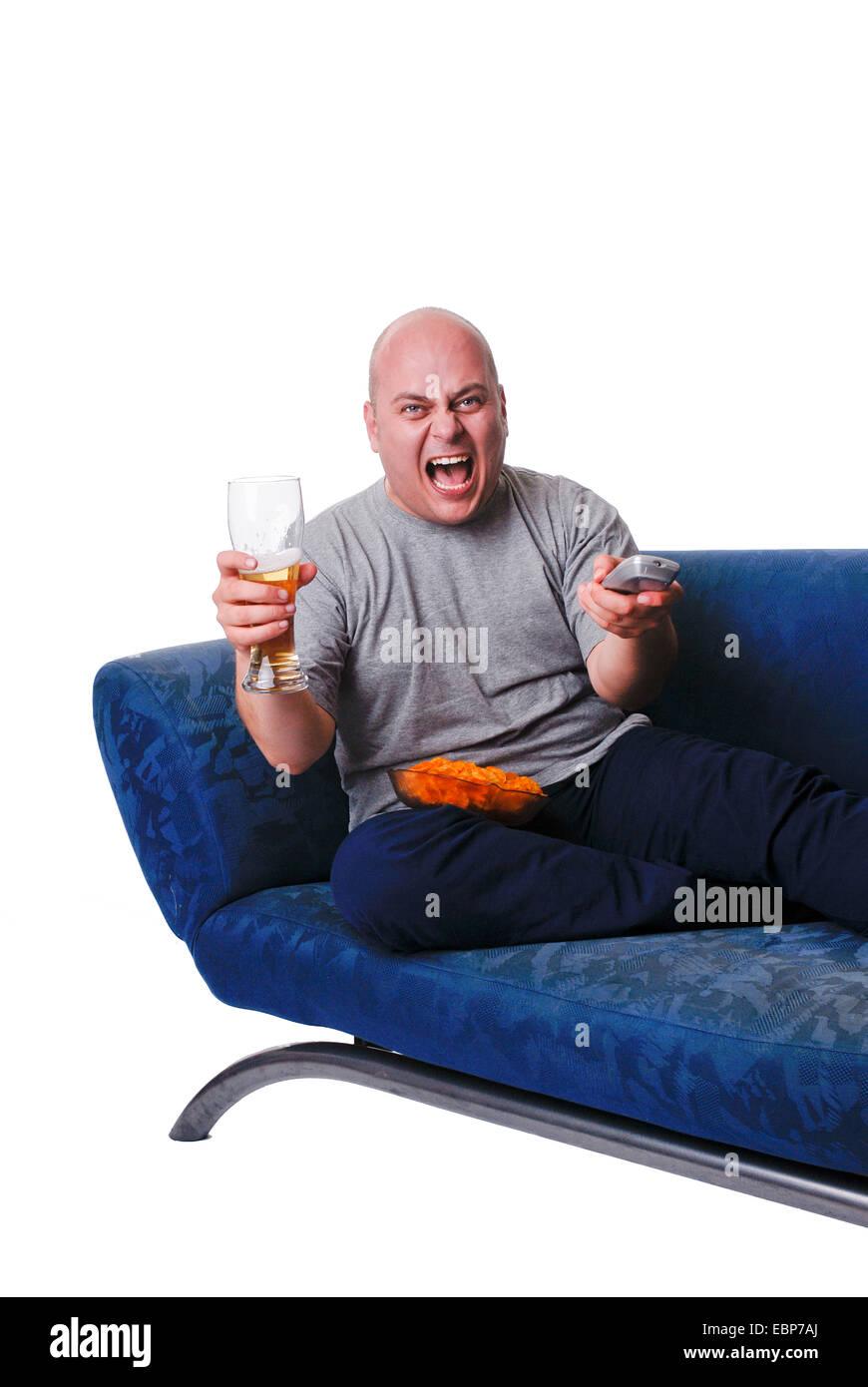 L'uomo con la birra, patatine e telecomando seduto sul divano Foto Stock