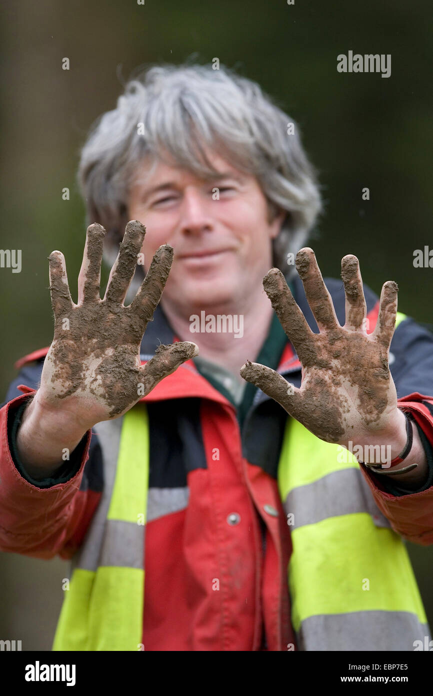 Uomo che mostra le mani fangose durante la piantagione di alberi sessione, Regno Unito, Scozia Foto Stock