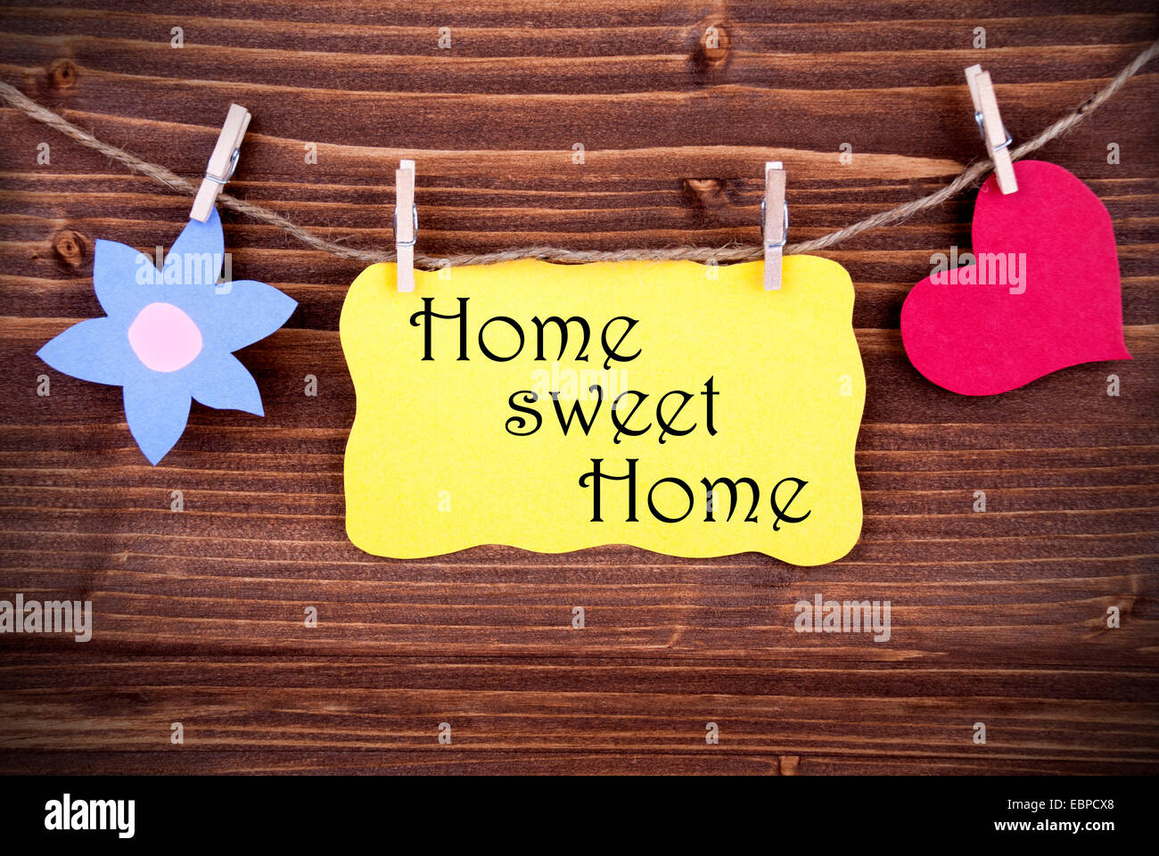 Giallo cartellino o etichetta con il cuore e con fiore su una linea con la vita Preventivo Home Sweet Home su sfondo di legno, due simboli, vintage, Foto Stock