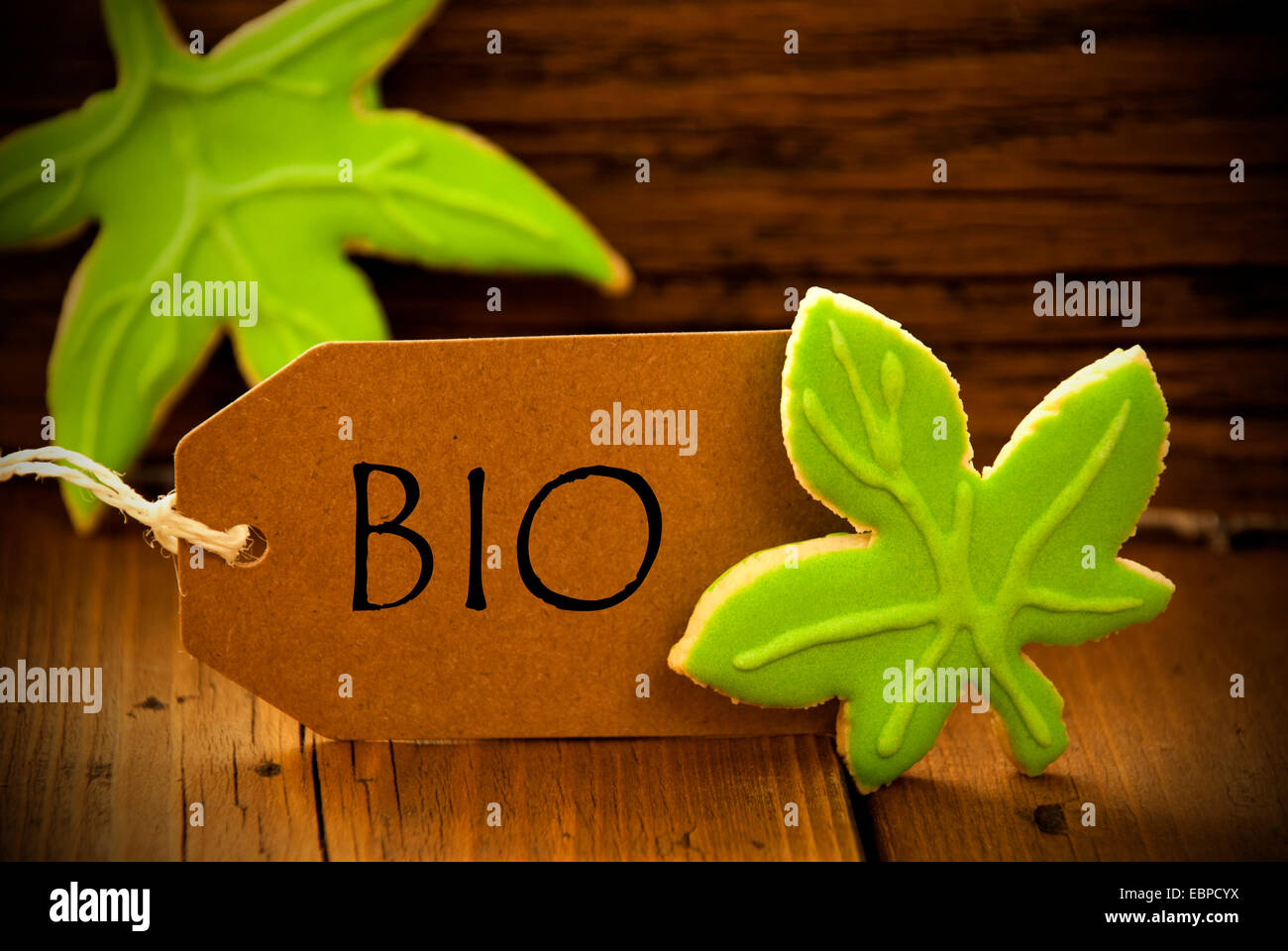 Brown organico etichetta con testo tedesco Bio su sfondo di legno con due foglie di Cookie e il telaio Foto Stock