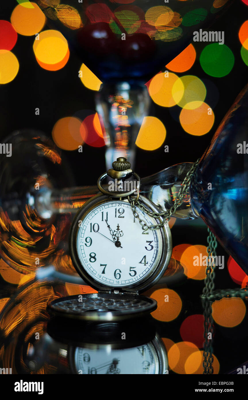 Felice Anno Nuovo cenone di capodanno con orologio da tasca con cinque a mezzanotte il tempo e il Martini cocktail bicchieri sul tavolo riflettente contro b Foto Stock