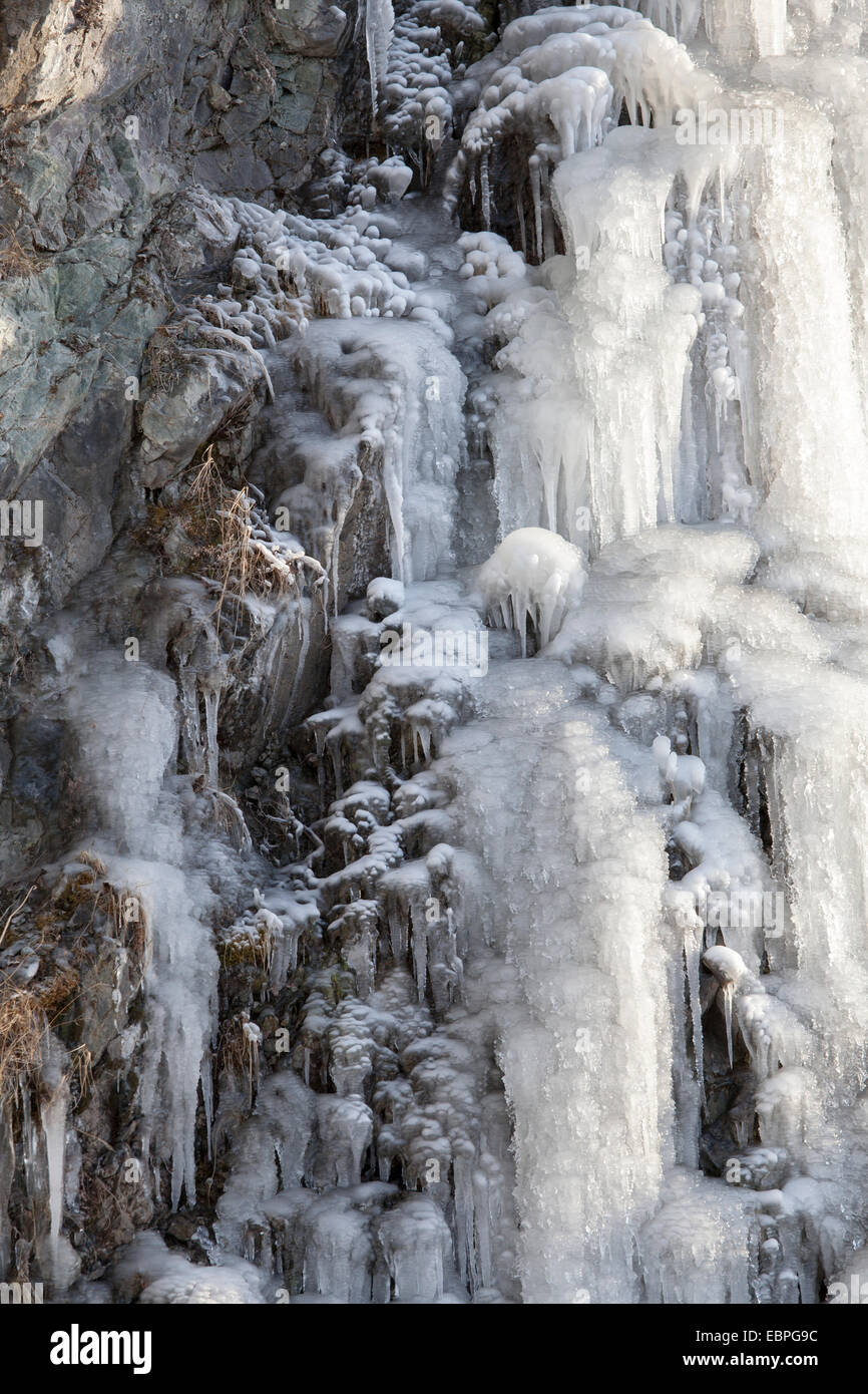 Cascata di ghiaccio su una ripida scogliera con modelli di magico nella luce del mattino. Foto Stock