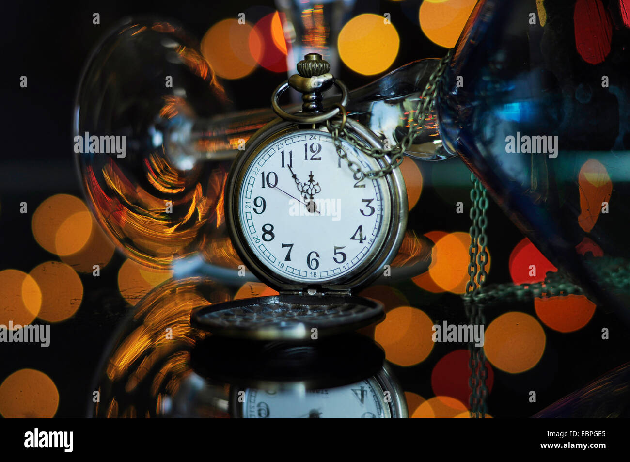 Felice Anno Nuovo cenone di capodanno con orologio da tasca con cinque a mezzanotte il tempo e il Martini cocktail bicchieri sul tavolo riflettente contro b Foto Stock