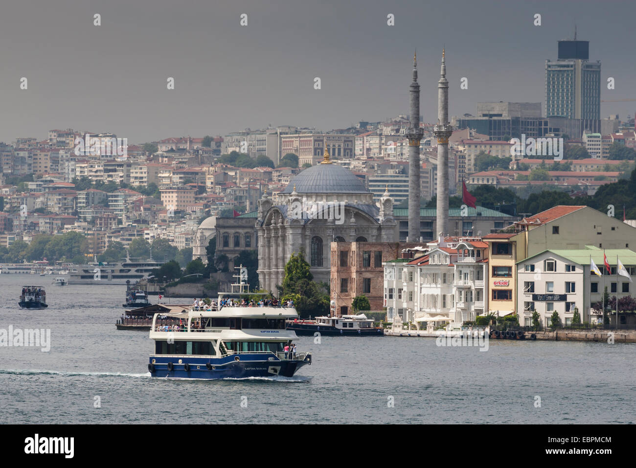 Ortakoy Mecidiye moschea e traghetti passeggeri, Ortakoy, da lo stretto del Bosforo con Istanbul skyline della città dietro, Istanbul, Turchia Foto Stock