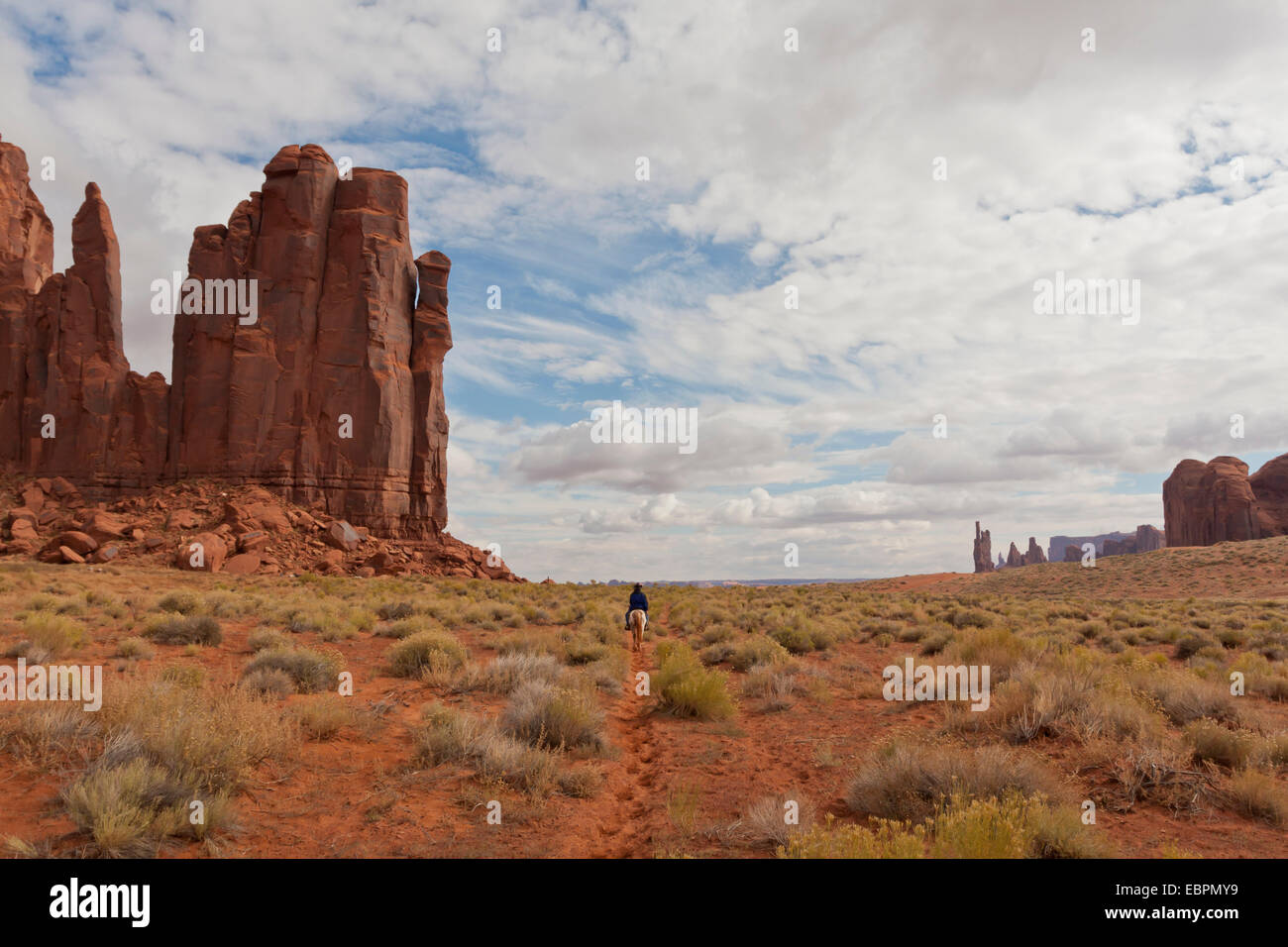 Persona Navajo passeggiate a cavallo tra le formazioni rocciose, il parco tribale Navajo Monument Valley, Utah Arizona, Stati Uniti d'America Foto Stock