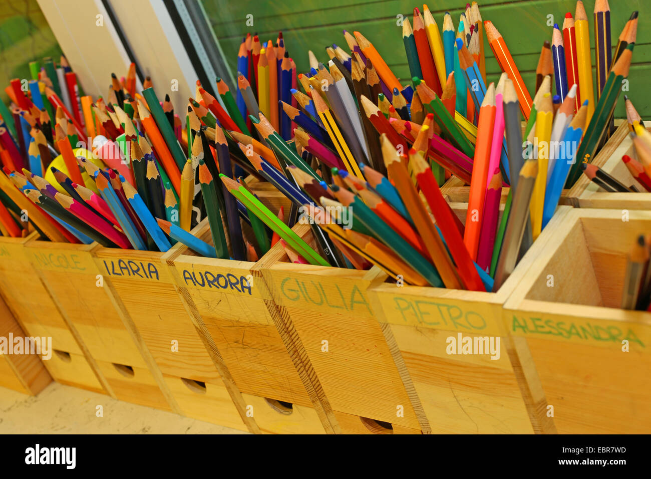 Molte matite colorate con i nomi dei bambini della scuola di classe Foto Stock