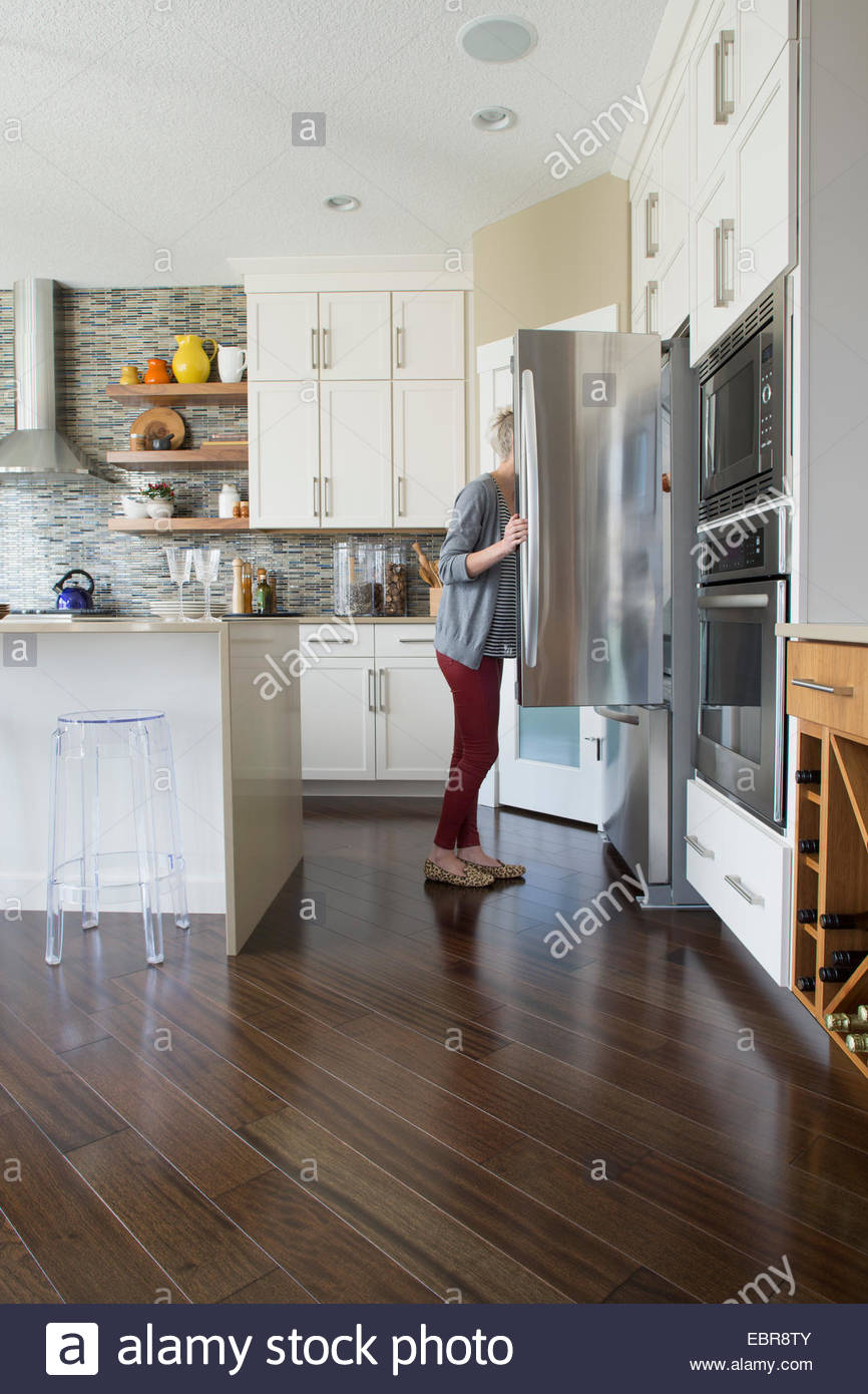 Donna del peering in frigorifero in cucina Foto Stock