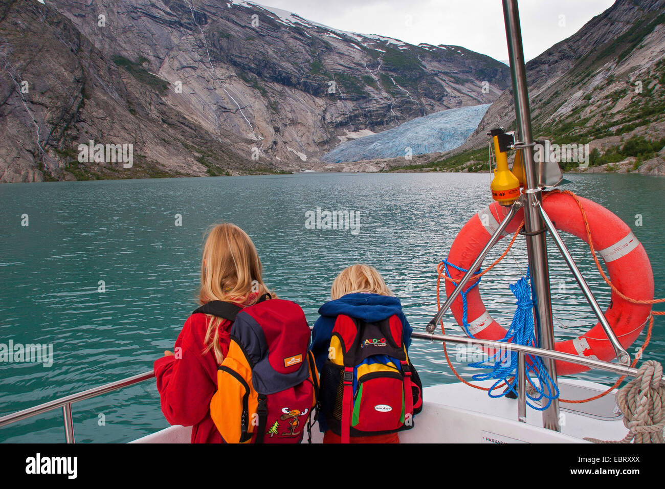 Due bambini su una nave sul lago glaciale Nigardsbrevatnet guardando alla lingua del ghiacciaio Nigardsbreen, Norvegia, Jostedalsbreen National Park, Jostetal Foto Stock