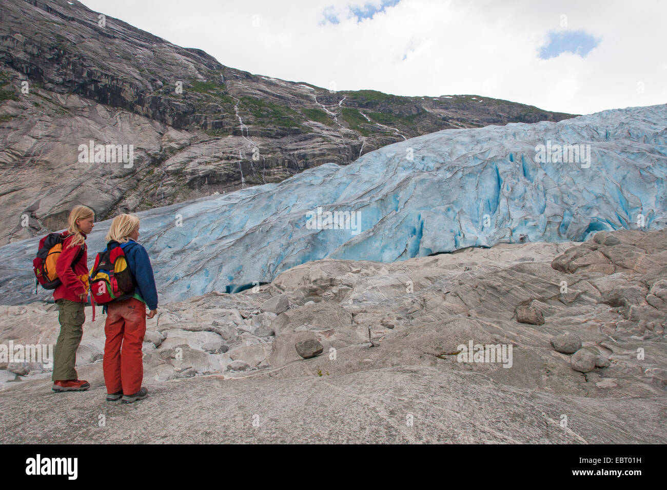 Due bambini in piedi di fronte del ghiacciaio Nigardsbreen lingua , Norvegia, Jostedalsbreen Parco Nazionale Foto Stock